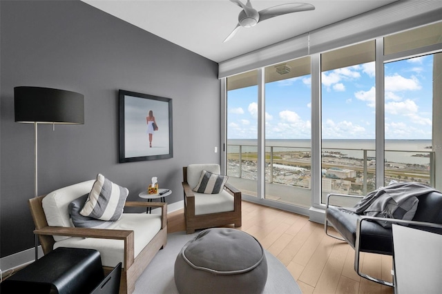 living area with a wealth of natural light, a wall of windows, and a water view