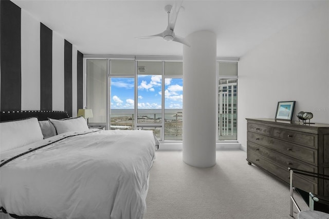 bedroom with ceiling fan, a wall of windows, and light colored carpet