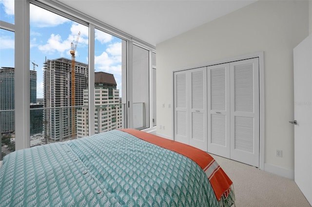 carpeted bedroom featuring a wall of windows and a closet