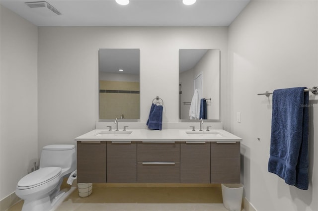 bathroom with toilet, vanity, and tile patterned flooring