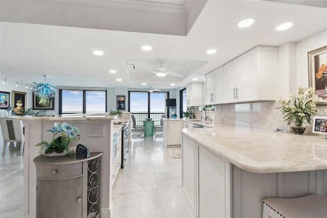 kitchen with recessed lighting, a raised ceiling, decorative backsplash, white cabinets, and a peninsula