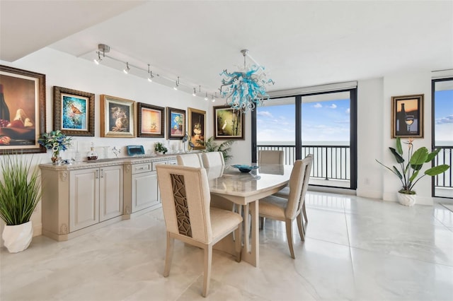 dining space with rail lighting, baseboards, and a notable chandelier