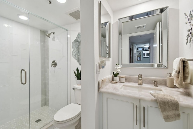 full bathroom featuring toilet, a stall shower, vanity, and visible vents