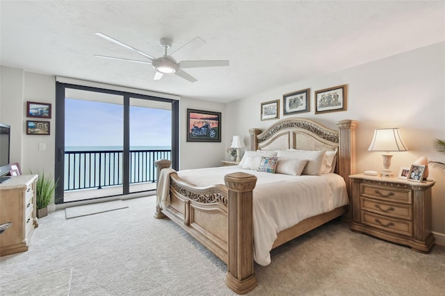 bedroom with light carpet, a ceiling fan, a water view, access to outside, and expansive windows