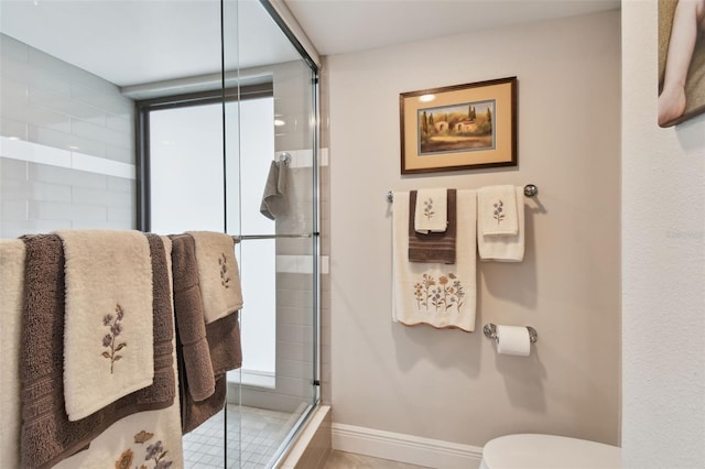 bathroom featuring a shower stall, toilet, and baseboards