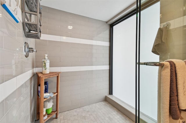 full bathroom with tiled shower and tile walls