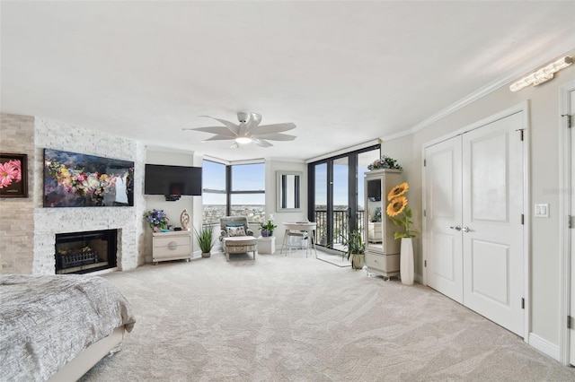 bedroom with ceiling fan, access to exterior, carpet, crown molding, and a stone fireplace