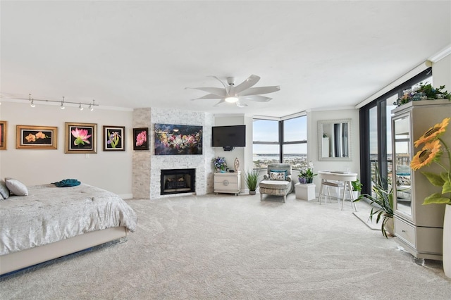 bedroom with a ceiling fan, rail lighting, a large fireplace, and carpet flooring