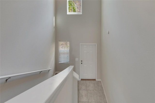 hallway featuring light tile patterned floors and a high ceiling