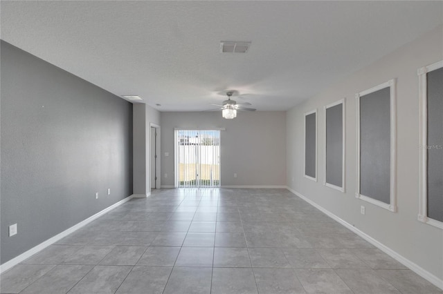 empty room featuring a textured ceiling, ceiling fan, and light tile patterned flooring