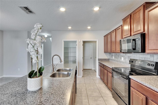 kitchen with tasteful backsplash, sink, light tile patterned floors, black appliances, and a textured ceiling