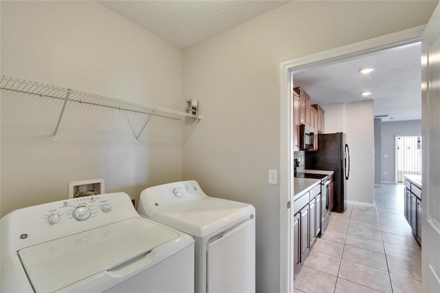 washroom with light tile patterned floors, washer and dryer, and a textured ceiling