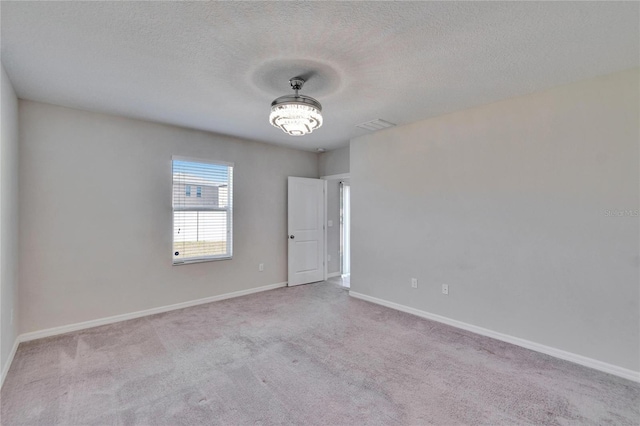 empty room with light colored carpet and a textured ceiling