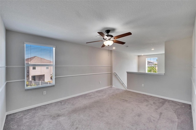 empty room with ceiling fan, light carpet, and a textured ceiling