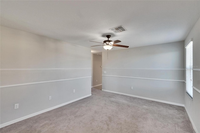 spare room featuring a textured ceiling, light colored carpet, and ceiling fan