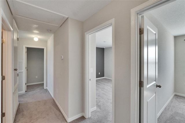 hallway featuring light carpet and a textured ceiling