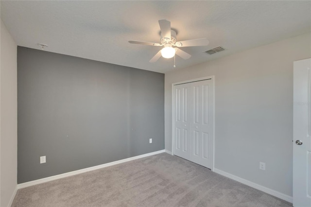 unfurnished bedroom with ceiling fan, light colored carpet, and a closet