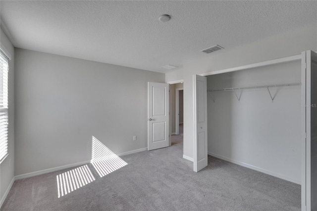 unfurnished bedroom featuring light colored carpet, a closet, and a textured ceiling