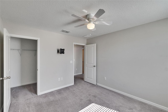 unfurnished bedroom with light carpet, a textured ceiling, ceiling fan, and a closet