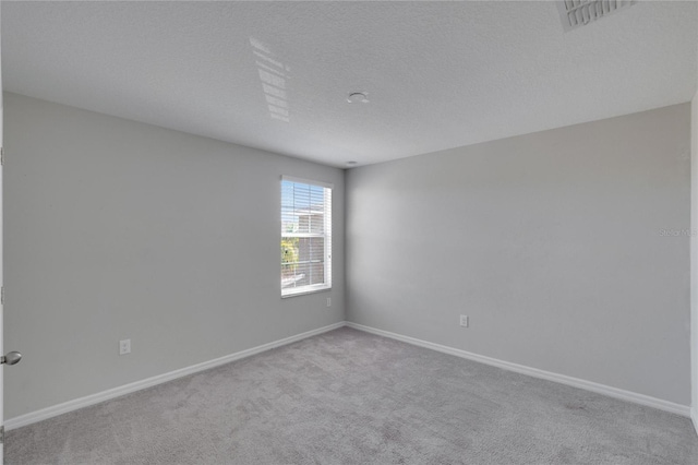 spare room featuring light carpet and a textured ceiling