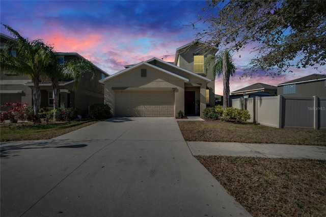 view of front of home featuring a garage, driveway, fence, and stucco siding