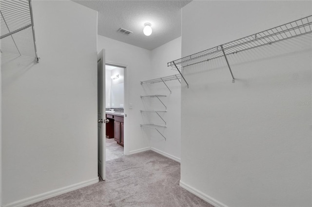 spacious closet with visible vents and light colored carpet