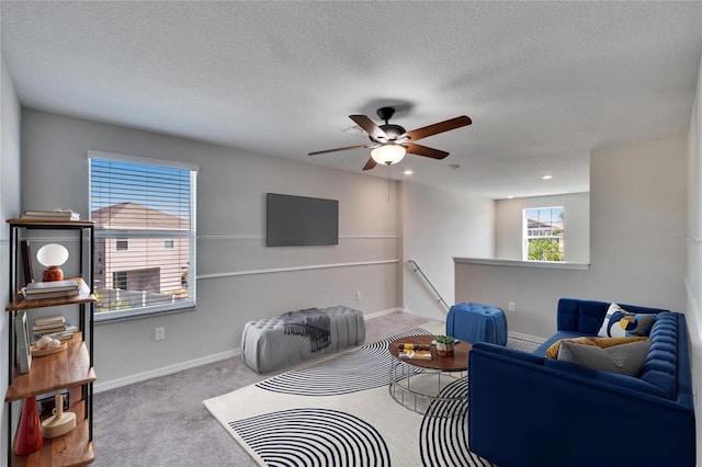 carpeted living area featuring ceiling fan, a textured ceiling, and baseboards