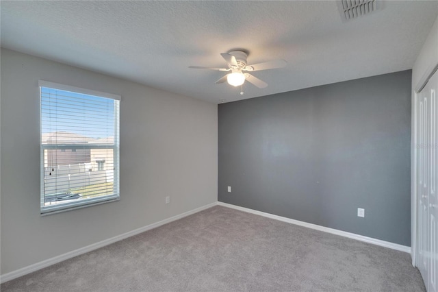 unfurnished room featuring baseboards, visible vents, a textured ceiling, and carpet flooring