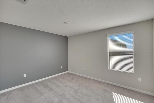 carpeted empty room featuring a textured ceiling and baseboards