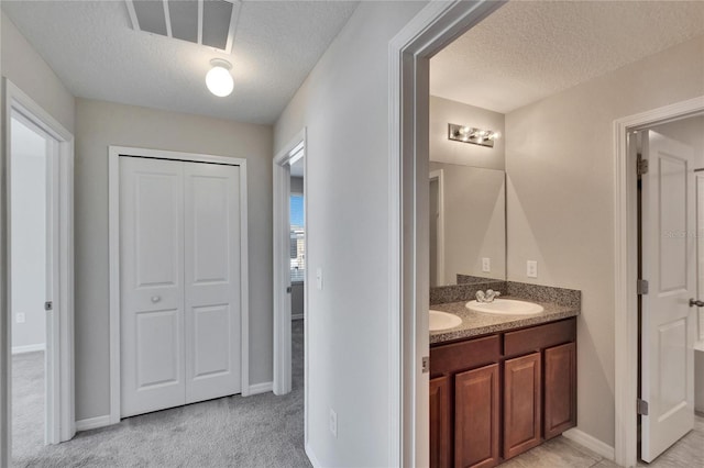 full bathroom with double vanity, visible vents, a sink, a textured ceiling, and baseboards