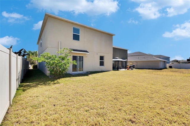 back of house featuring a lawn, a fenced backyard, and stucco siding