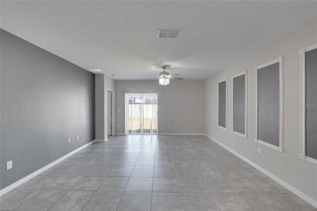 empty room with baseboards, light tile patterned floors, visible vents, and a ceiling fan