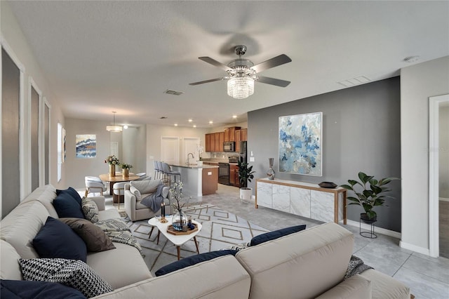 living area featuring a ceiling fan, visible vents, baseboards, and light tile patterned floors