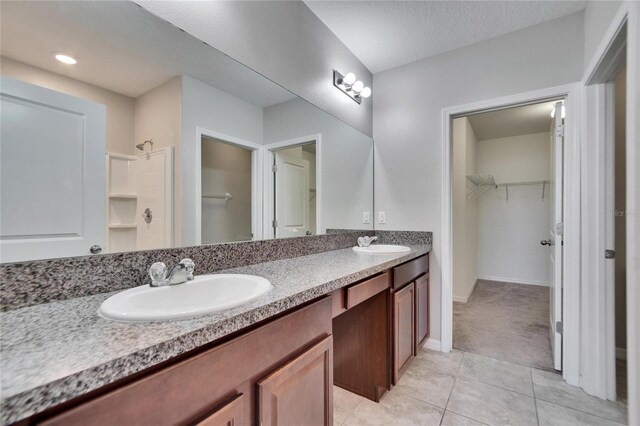 full bathroom with walk in shower, a sink, a spacious closet, and double vanity