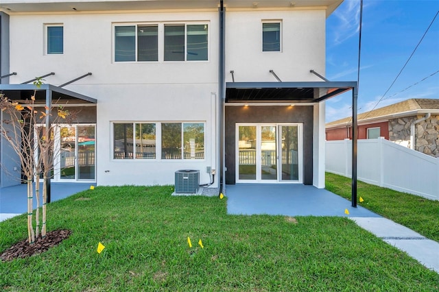 rear view of property featuring cooling unit, a lawn, and a patio