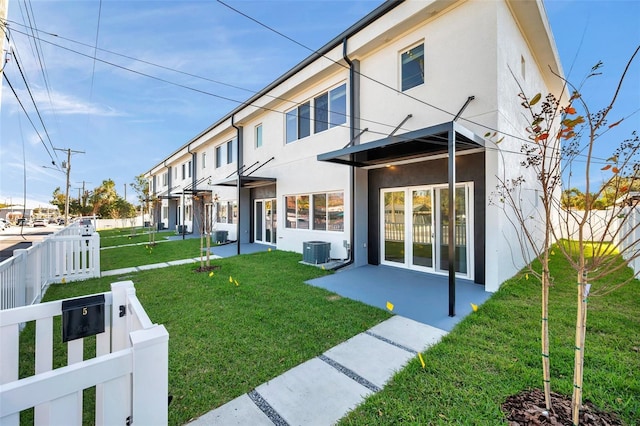 rear view of property featuring central AC, a lawn, and a patio