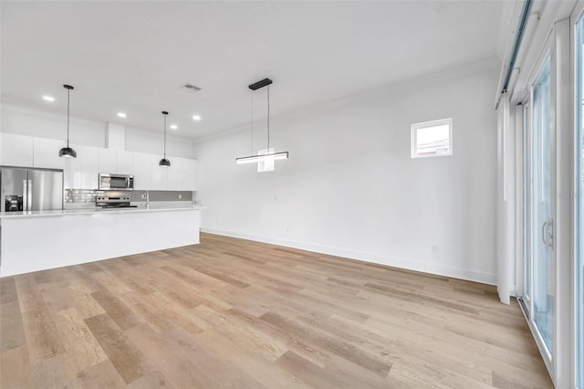 unfurnished living room featuring sink, crown molding, and light hardwood / wood-style flooring