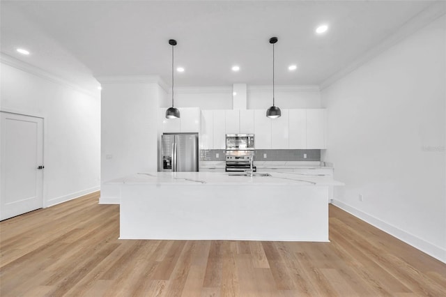 kitchen with light stone countertops, white cabinetry, stainless steel appliances, hanging light fixtures, and a kitchen island with sink