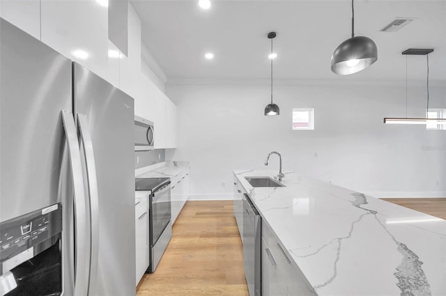 kitchen with stainless steel appliances, pendant lighting, white cabinetry, and sink