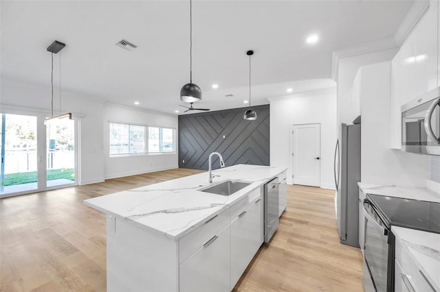 kitchen with decorative light fixtures, white cabinets, an island with sink, and sink