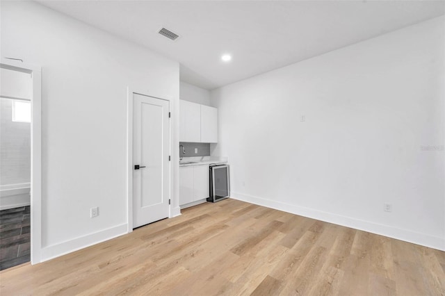 kitchen featuring white cabinetry, light hardwood / wood-style flooring, and wine cooler