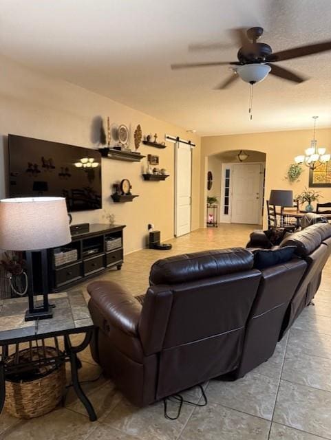 living room featuring a barn door and ceiling fan with notable chandelier