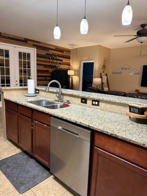 kitchen with dishwasher, sink, hanging light fixtures, wood walls, and light tile patterned floors