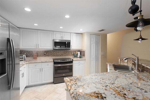 kitchen featuring white cabinetry, sink, decorative backsplash, stainless steel appliances, and light stone countertops