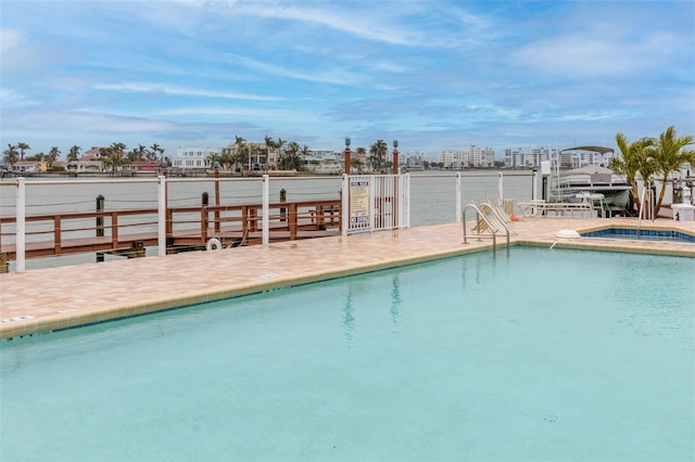 view of swimming pool featuring a water view and a hot tub