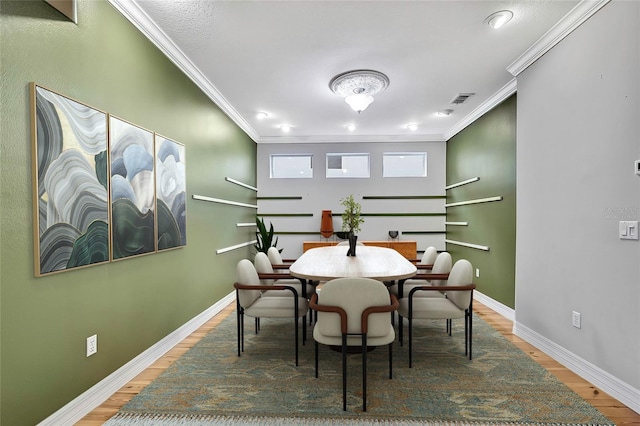 dining space featuring wood-type flooring and crown molding