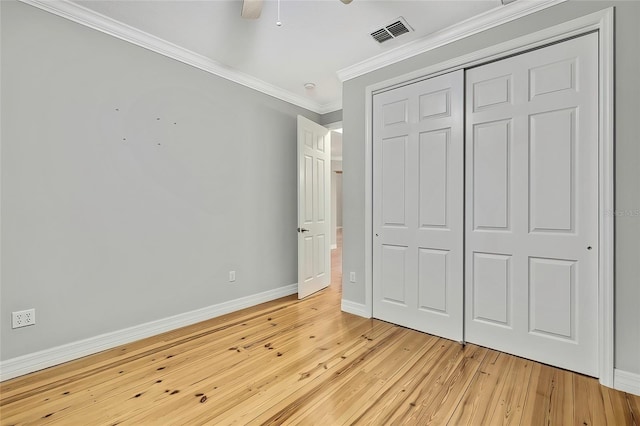 unfurnished bedroom with ceiling fan, a closet, ornamental molding, and light wood-type flooring