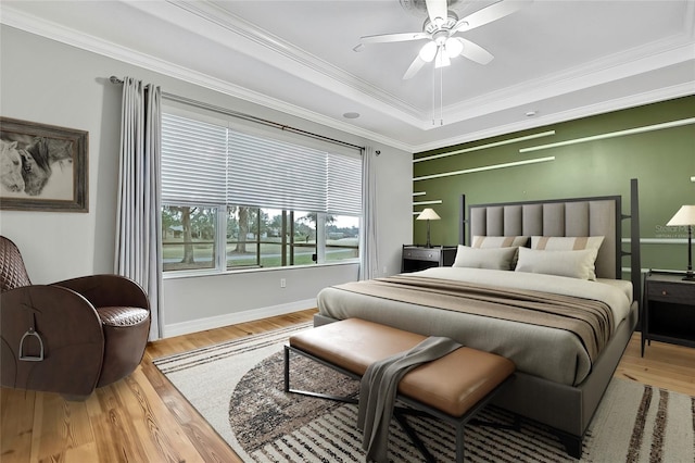 bedroom with ceiling fan, light wood-type flooring, crown molding, and a raised ceiling