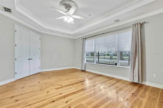 unfurnished bedroom with ceiling fan, ornamental molding, a raised ceiling, and light hardwood / wood-style flooring