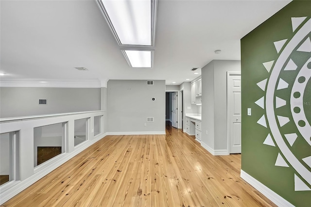 unfurnished living room featuring built in shelves and light hardwood / wood-style floors